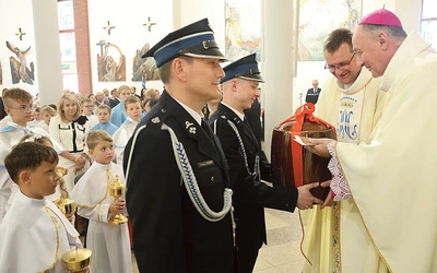 W procesji z darami strażacy przynieśli naczynie na wodę święconą. 
