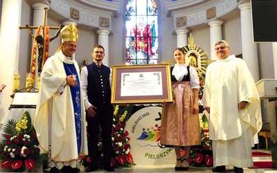  Bp Roman Pindel i ks. kustosz Janusz Talik przy jubileuszowym dekrecie, przyniesionym przez młodych parafian w strojach regionalnych.