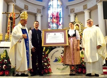  Bp Roman Pindel i ks. kustosz Janusz Talik przy jubileuszowym dekrecie, przyniesionym przez młodych parafian w strojach regionalnych.
