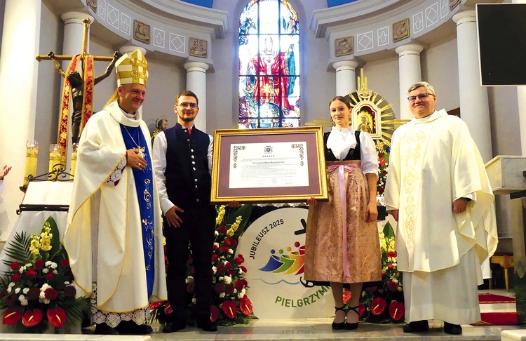  Bp Roman Pindel i ks. kustosz Janusz Talik przy jubileuszowym dekrecie, przyniesionym przez młodych parafian w strojach regionalnych.