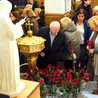 Wierni składają róże przed figurą świętej.