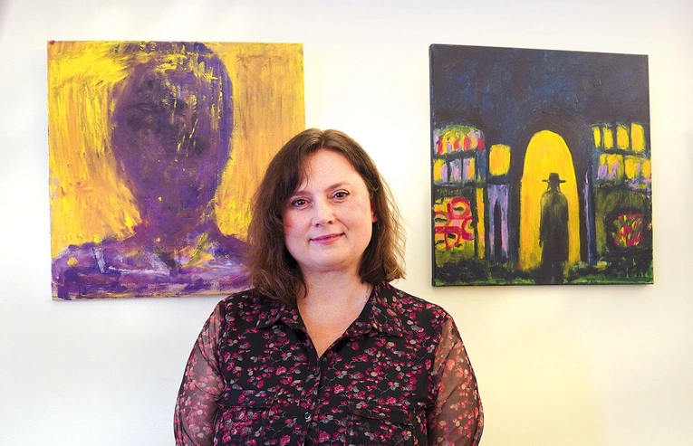 Agnieszka Paluch obok obrazów „Spotkanie Nikodema z Jezusem”  oraz „Autoportret”. 