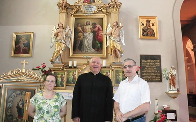 Proboszcz wspólnoty ks. Józef Milan i jej historycy – dr Barbara Hryszko i prof. Rafał Hryszko – przed ołtarzem patrona.