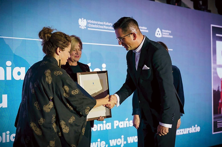 Ojciec proboszcz odbiera wyróżnienie od przedstawicieli resortu.