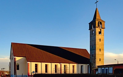 Prosta bryła kościoła z wieżą i dużymi oknami tworzy jasną przestrzeń modlitwy. 