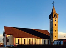 Prosta bryła kościoła z wieżą i dużymi oknami tworzy jasną przestrzeń modlitwy. 