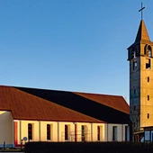 Prosta bryła kościoła z wieżą i dużymi oknami tworzy jasną przestrzeń modlitwy. 