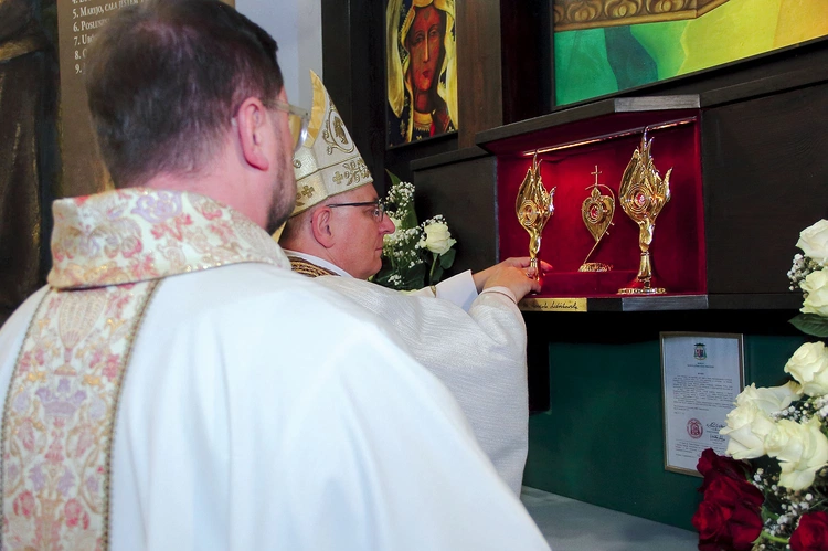 Biskup wraz z proboszczem zainstalowali relikwiarze w specjalnej gablocie.