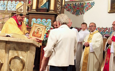 Biskup tarnowski Andrzej Jeż poświęconą ikonę patrona przekazuje pierwszej rodzinie, od której rozpoczęła się peregrynacja.
