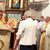 Biskup tarnowski Andrzej Jeż poświęconą ikonę patrona przekazuje pierwszej rodzinie, od której rozpoczęła się peregrynacja.