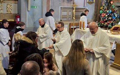 Ks. J. Kucharski (w środku) rozdaje zakładki „Jak czytać Pismo Święte”.