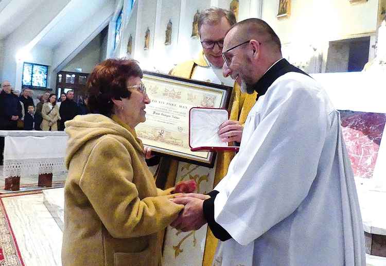 Grażyna Nalepa przyjmuje medal Stolicy Apostolskiej z rąk kanclerza ks. Adama Bieńka (z prawej). W środku, ze stosownym dyplomem – proboszcz ks. Stanisław Wójcik.