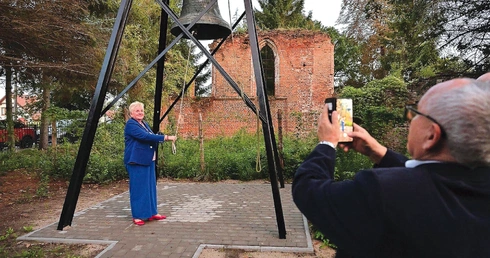 Historyczny dzwon, a w tle pozostałości gotyckiej budowli.