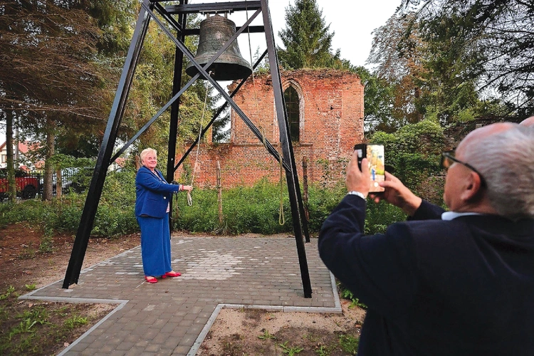 Historyczny dzwon, a w tle pozostałości gotyckiej budowli.